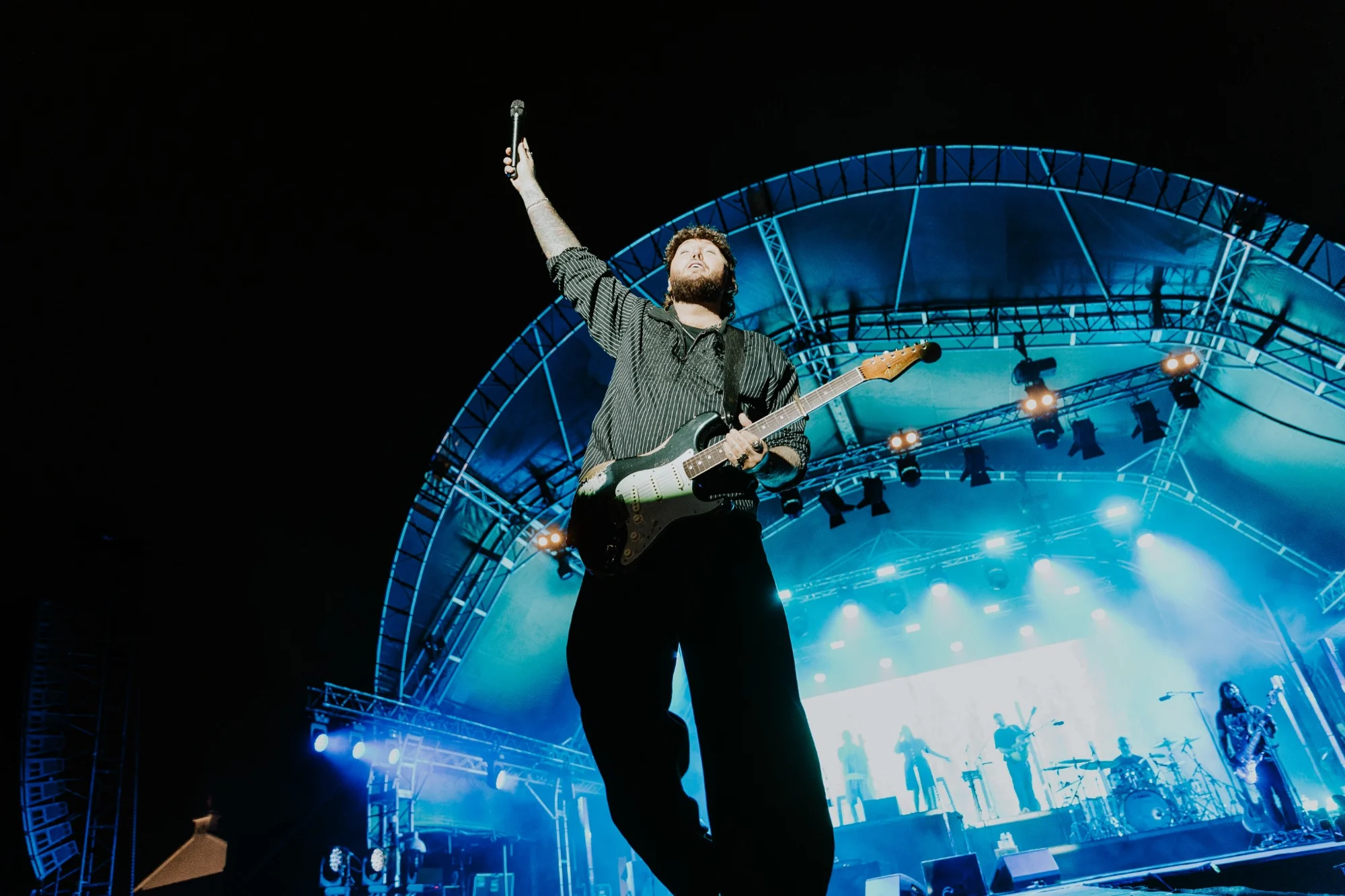 James Arthur with his guitar under blue stage lights